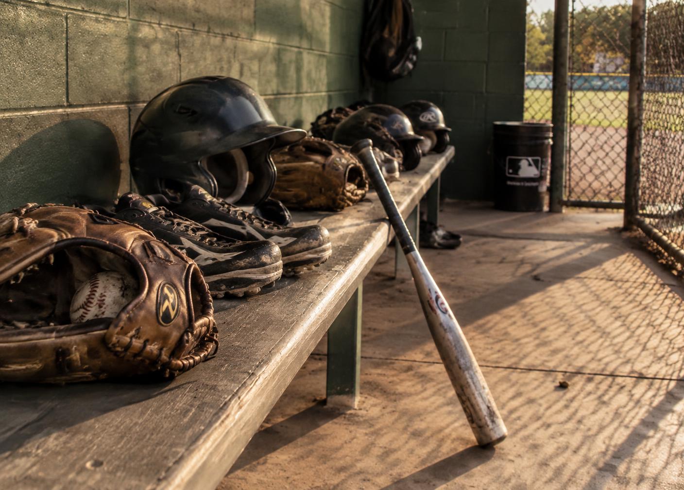 A youth baseball team huddled with their coach at dusk